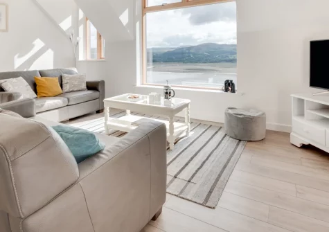 Apartment 4, The Old Stables, Aberdovey is a stylish two-bedroom retreat with panoramic Dyfi Estuary views. Enjoy a private decked patio, dog-friendly comfort and easy reach of Snowdonia's beaches and mountains, perfect for families and couples.