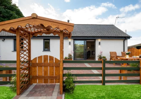 The enclosed patio & alfresco dining area, with access to the field to execise your dogs, at Bryniau Pair Ucha Cottage, Pandy Tudur