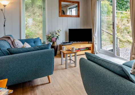 Dragonfly Lodge, Tyn-y-Groes is a stylish two-bedroom lodge set within three tranquil acres near Conwy, featuring a private patio with valley views, cosy interiors, and easy access to Snowdonia's castles, mountains, beaches and coastline.