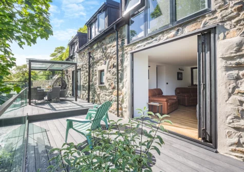 The riverside decked terrace & outdoor sitting area at Drws Y Coed, Capel Curig