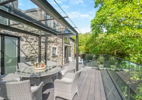 The riverside decked terrace & alfresco dining area at Drws Y Coed, Capel Curig