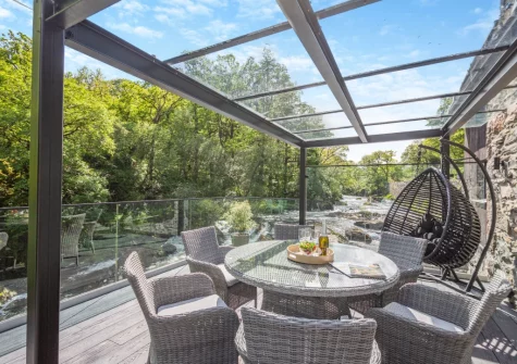 The riverside riverside decked terrace & alfresco dining area at Drws Y Coed, Capel Curig