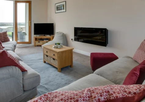 Ger y Bont, Valley is a spacious four-bedroom house on the shores of the Cymyran Strait, Anglesey, with a glass balcony framing ever-changing tidal views, elegant contemporary interiors, an enclosed garden, and private parking for four cars.