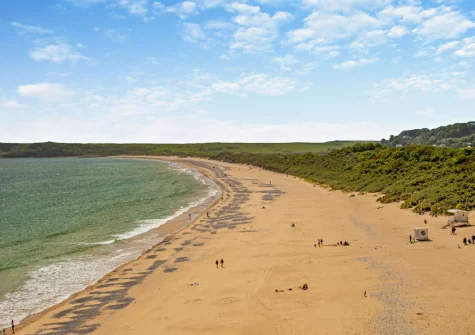 Visit Tenby South Beach, featuring a long sandy coastline with dunes & shallow waters