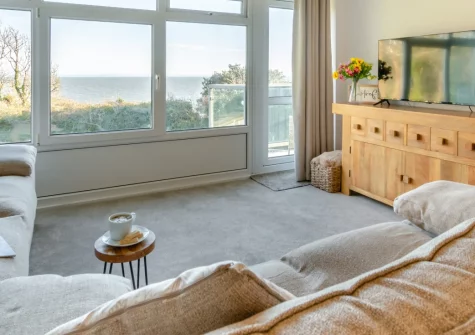 Mor Glas View, Tenby is a beautifully appointed seafront apartment overlooking North Beach and the historic harbour, featuring two private balconies with sea views, contemporary coastal interiors, and direct access to golden sands & the town centre.