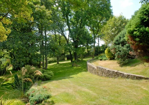 The farmhouse lawned garden, dotted with mature trees, at The Hayloft, Broad Haven