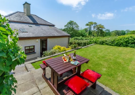 The patio, alfresco dining area & terraced lawn garden at The Lodge, Llanfaglan