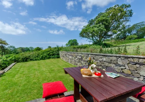 The patio, alfresco dining area & terraced lawn garden at The Lodge, Llanfaglan