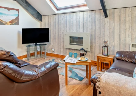 The Mews, Tenby is a charming first-floor apartment within the historic town walls, featuring exposed beams and skylights, contemporary coastal living, and North Beach's golden sands just 300 metres from your door in this Pembrokeshire town.