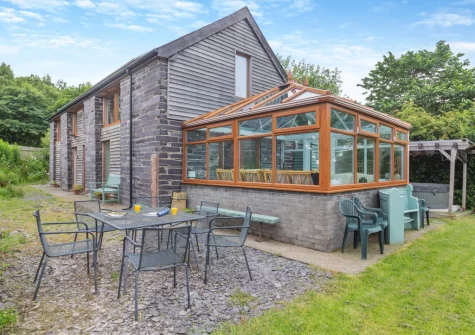 The alfresco dining, outdoor sitting area, hot tub & garden at Ty Gwair, St Anns Bethesda
