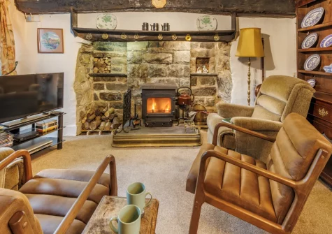 Ty'n Lon Isaf, Bontddu is a characterful riverside longhouse in Eryri National Park, offering exposed beams, a cosy wood burner, a sprawling multi-level garden with direct river access, and a games room for unforgettable family holidays.