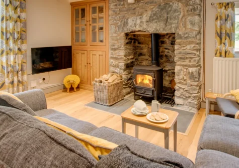 Y Felin, Llanymawddwy is a charming stone-built cottage tucked down a private lane in southern Snowdonia, featuring beamed ceilings, an inglenook wood burner, a lawned garden with river access, and glorious mountain walks right on the doorstep.